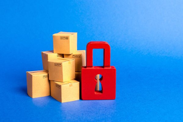 A stack of cardboard boxes and a red padlock. concept of insurance purchases. Consumer rights Protection. cargo arrest customs clearance. ban on the import. Providing warranty on purchased products. A stack of cardboard boxes and a red padlock. concept of insurance purchases. Consumer rights Protection. cargo arrest customs clearance. ban on the import. Providing warranty on purchased products.